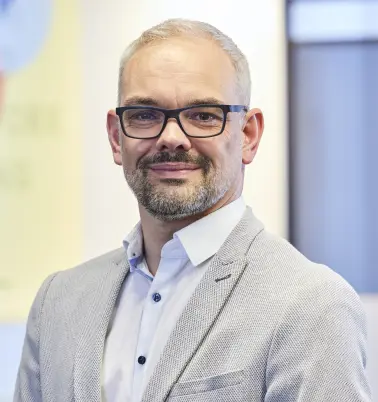 Oliver Fischer schaut nach vorne und lächelt. 