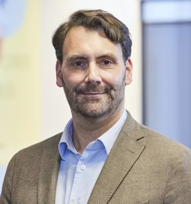 Roland Quinten schaut nach vorne und lächelt. 