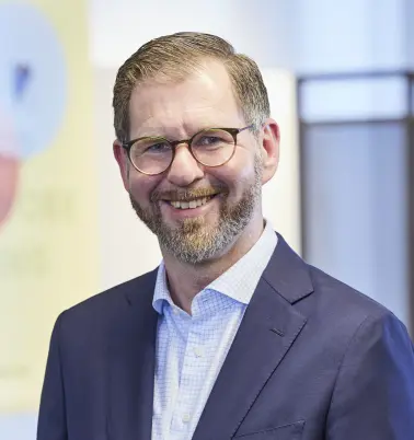 Sebastian Lütje schaut nach vorne und lächelt. 